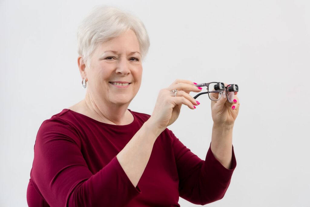 Woman holding a pair of bioptic eyeglasses