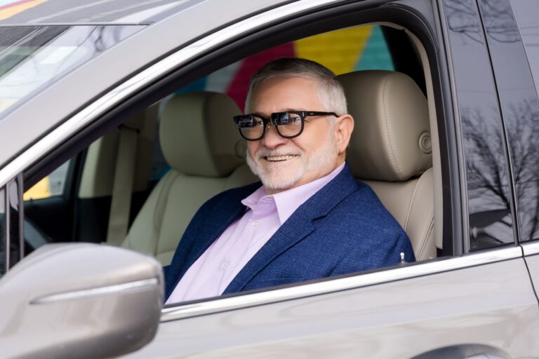A man wearing low vision glasses in the drivers seat of a car